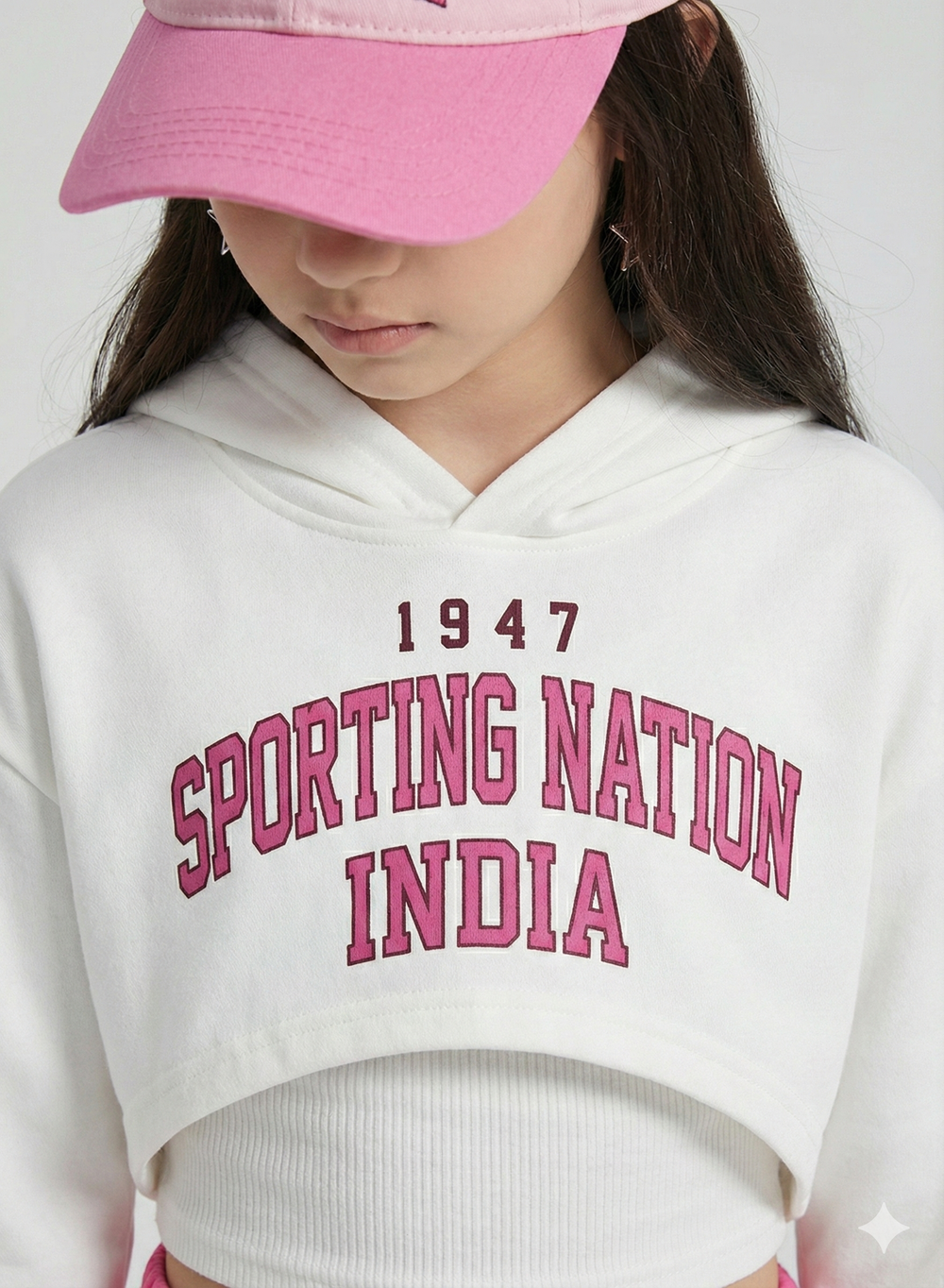 Person wearing a white hoodie with '1947 Sporting Nation India' text and a pink cap.